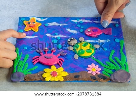 Children's clay sculptures depicting the sea with flowers, corals, and crabs, fish and turtles are aquatic creatures that inhabit the sea.