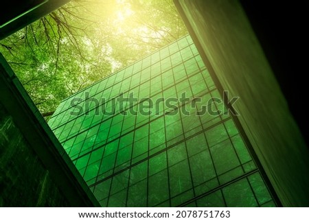 Eco-friendly building in the modern city. Sustainable glass office building with tree for reducing heat and carbon dioxide. Office building with green environment. Corporate building reduce CO2.  Royalty-Free Stock Photo #2078751763