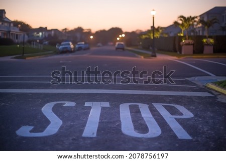 Stop pavement marking warning to halt against the line at urban intersection, prohibiting further advancement. Traffic sign on asphalt restricting movement without stopping to avoid car accident. 