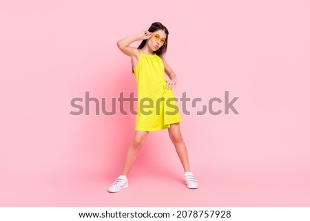Full length photo of shiny cute school girl wear yellow dress dark eyewear sending you kiss dancing isolated pink color background