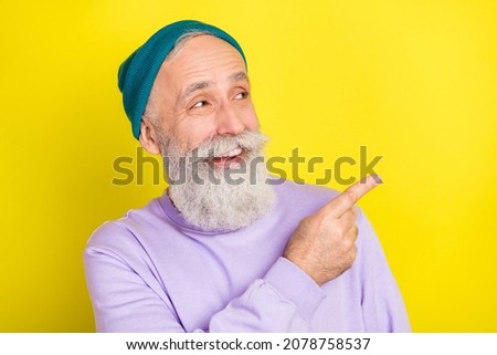 Photo portrait of amazed senior man pointing empty space smiling cheerful isolated bright yellow color background