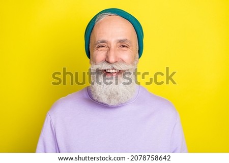 Photo of funky cool mature man dressed purple pullover headwear smiling isolated yellow color background