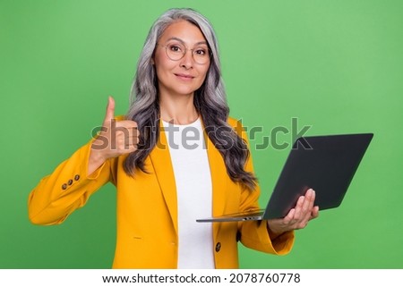 Photo of senior woman hold laptop show thumb-up choice suggest advert attorney isolated over green color background