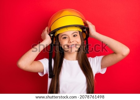 Photo of young girl happy positive smile hands touch helmet firewoman isolated over red color background