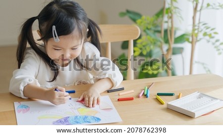 Asian child drawing pictures at home