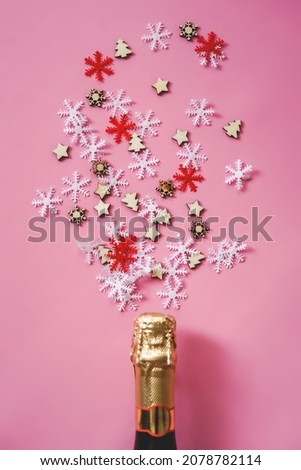 Christmas and New Year flatlay. Champagne bottle, wood star and snowflakes confetti on pink background top view. Flat lay holiday card. Birthday or party concept. Festive decorations