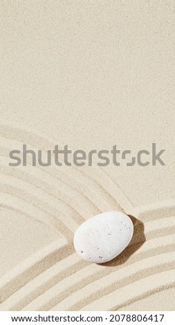 Zen garden meditation sandy background with copy space. White stone and lines on sand for balance and harmony or spa wellness. Vertical format for stories.