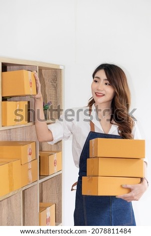 Asian woman starting a small SME business working on boxes and laptops preparing parcels for shipping. and the concept of working from home, collecting parcels, packing boxes in vertical order