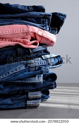 a pile of blue and pink jeans on a gray background. Close up