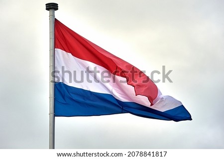The flag of the Netherlands hangs on a metal flagpole