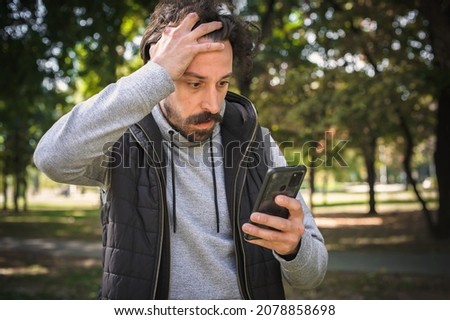 The young man received a very bad and disturbing message on his mobile phone. He is very stunned and shocked and can't believe what he saw Royalty-Free Stock Photo #2078858698