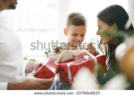 Smiling parents giving Christmas present to son at home