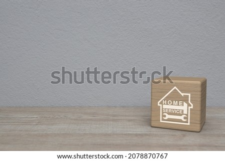 Hammer and wrench with house flat icon on wood block cube on wooden table over white wall background, Business home service concept