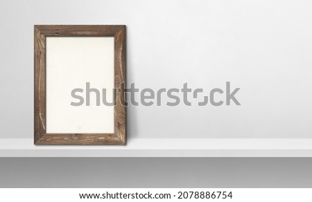 Wooden picture frame leaning on a white shelf. 3d illustration. Blank mockup template. Horizontal banner