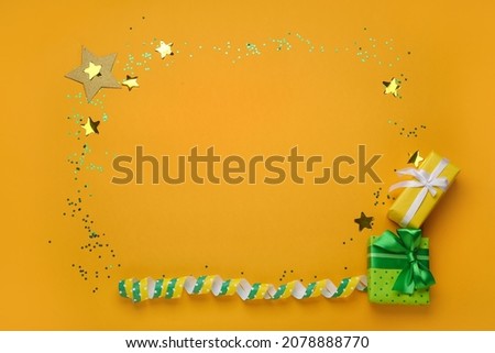 Frame made of gift boxes and confetti on color background