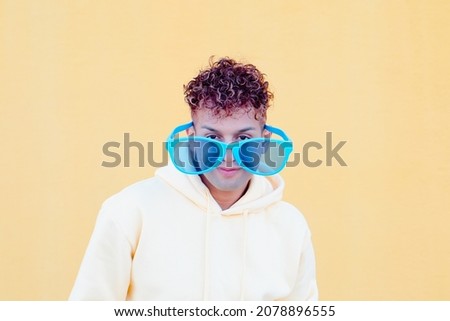 Funny picture : Latin guy with big glasses looking at camera with yellow background