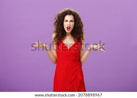 Woman being shocked guy breaking up with her during party. Concerned pissed and outraged good-looking lady in red dress with evening makeup shrugging with spread palms in clueless and questioned pose Royalty-Free Stock Photo #2078898967