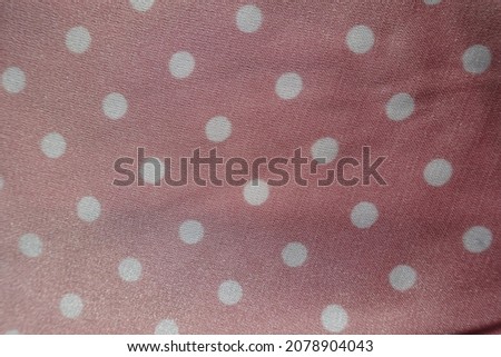 Texture of pink and white satin polyester fabric with polka dot pattern