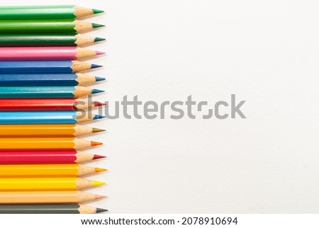 Different colored pencils are placed on a white background. and crayons alternating close-up, top view, concept art, text and office copy space.