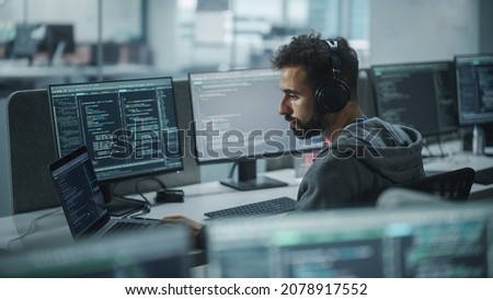Office: Professional White IT Programmer Uses Headphones while Working on Desktop Computer. Male Website Developer, Software Engineer Developing App, Video Game. Listening to Podcast, Music.