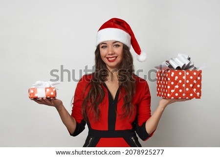 Young woman in red santa claus hat holding present box. Beautiful woman with christmas gifts box on white background with copy space