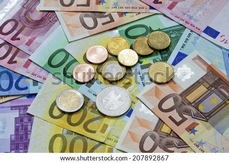 Euro coins on heap of euro notes