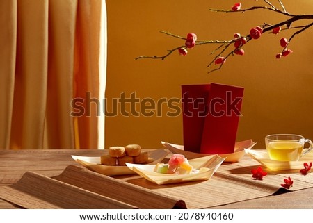 Chinese new year with red pocket teapot and biscuit in blue background for Tet holiday advertising , front view , holiday content Royalty-Free Stock Photo #2078940460