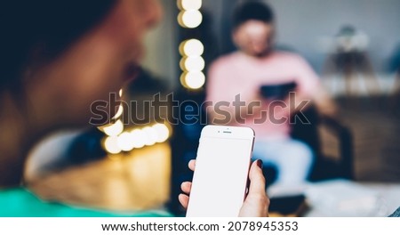 Unrecognizable female blogger using home internet connection on mockup smartphone technology with copy space area for advertising text, woman browsing website on cellular phone with blank touchscreen