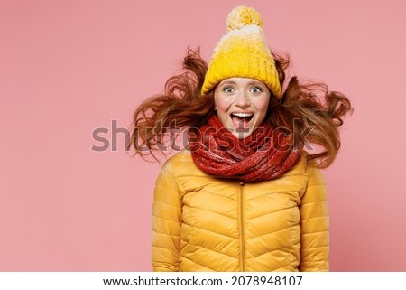 Shocked surprised amazed young woman 20s wears yellow jacket hat mittens keeping mouth wide open jumping have fun enjoy fluttering hair isolated on plain pastel light pink background studio portrait Royalty-Free Stock Photo #2078948107