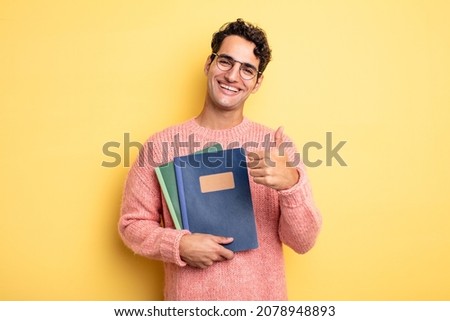 young handsome man feeling proud,smiling positively with thumbs up. notebook concept