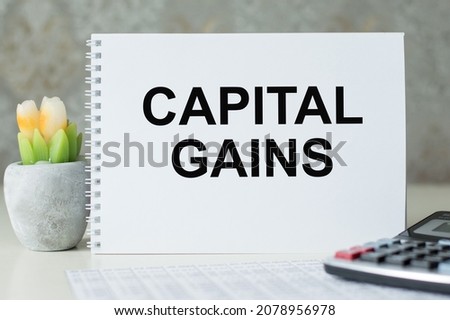 Capital Gains. Business concept. Text on white notepad paper on light background