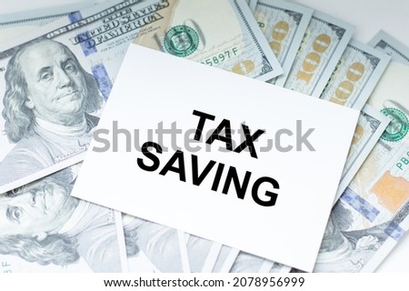 White paper with text TAX SAVING with dollars on table, business concept