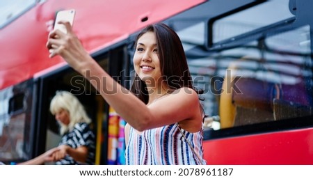 Cheerful millennial user smiling at front mobile camera while shooting video content for sharing to social media networks enjoying travel vacations during summertime,happy blogger making selfie photos