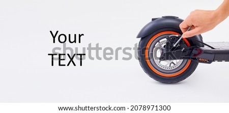 Hand repairing electrical scooter on white background. Special workshop for repairing electrical escooters. Technological concept. Royalty-Free Stock Photo #2078971300