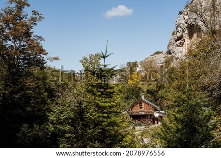 Wooden house in the forest among the mountains. Grotto in a mountainous environment. Bright sunny day in the mountains, a walk through the forest to the forester's house. Spruce and pine.  Royalty-Free Stock Photo #2078976556