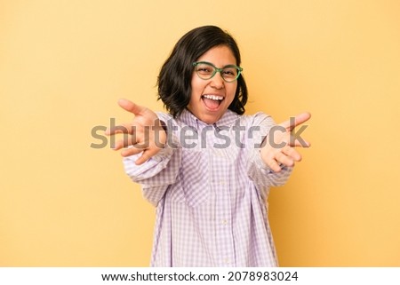 Young latin woman isolated on yellow background feels confident giving a hug to the camera.