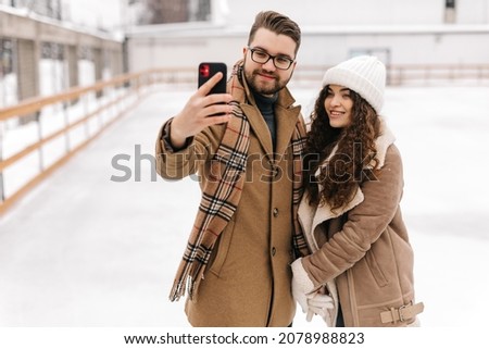 Close up photo of happy couple taking a selfie in a figure skating field