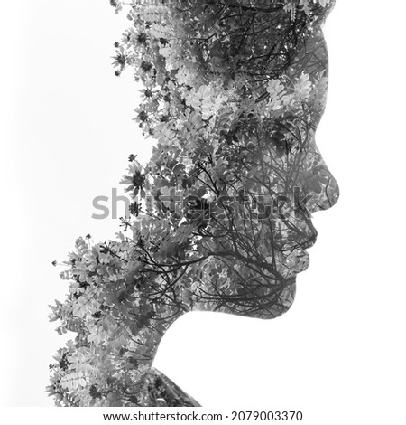 A black and white profile portrait of a handsome woman combined with twigs of wildflowers in a double exposure technique. Dissolving into nature.