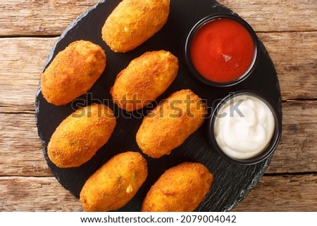 Croquetas de Bacalao Cod Croquettes with sauces close up in the slate plate on the table. Horizontal top view from above
