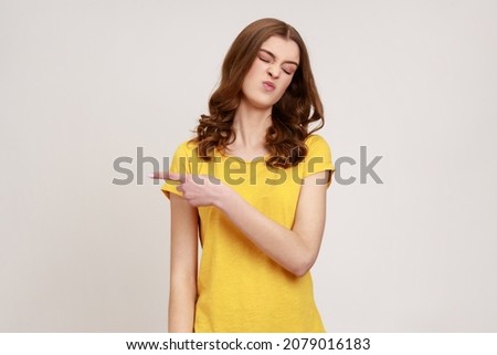 Get out! Portrait of upset vexed woman of young age with wavy hair showing exit, demanding to leave her alone, has resentful irritated expression. Indoor studio shot isolated on gray background. Royalty-Free Stock Photo #2079016183