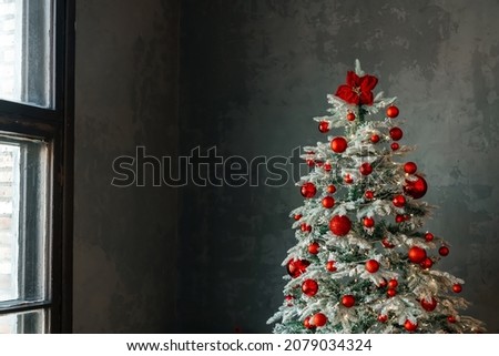 An elegant Christmas tree is decorated with glittering glass balls, beads and garlands. High quality photo