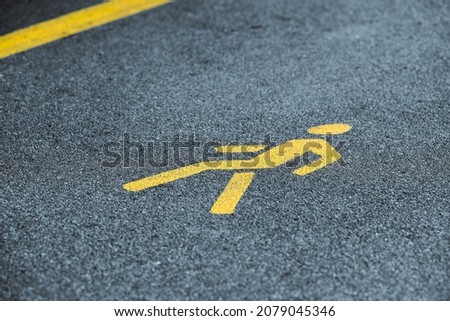 Yellow pedestrian sign on sidewalk, safe road traffic near highway. Pedestrian road sign on asphalt track, yellow marking for road traffic safety, selective focus