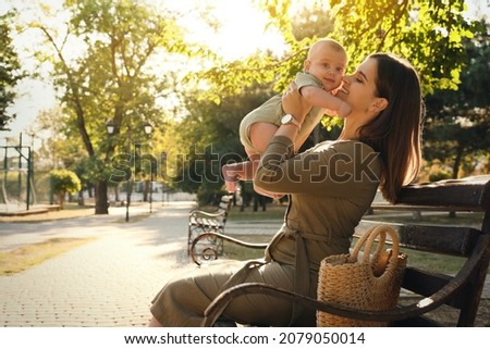 Young mother with her cute baby on bench in park