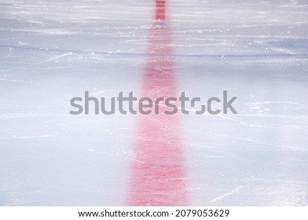 Clean empty ice hockey rink. Skate blade marks and snow crumbs. Marking lines are visible.