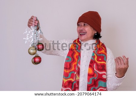 Indonesian woman in white warm clothes holding some Christmas ornaments
