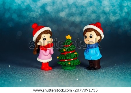 New Year's idea. Figurines of children at the Christmas tree on a blue background. Holiday Toys