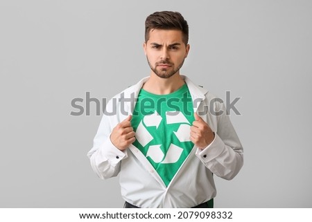 Man wearing t-shirt with recycling sign on grey background. Ecology concept