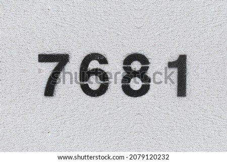 Black Number 7681 on the white wall. Spray paint. Number seven thousand six hundred and eighty one.