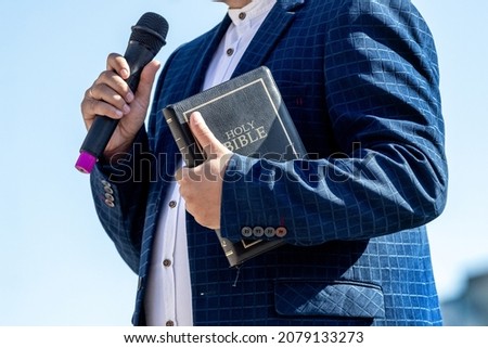 Pastor with a Bible in his hand during a sermon. The preacher delivers a speech Royalty-Free Stock Photo #2079133273