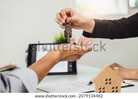 Realtor agent giving a key of apartment to new owner after signed lease agreement.